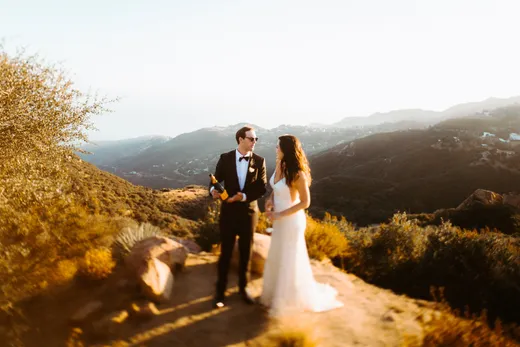 Bride and groom opening champagne on a Topanga Canyon trail at sunset