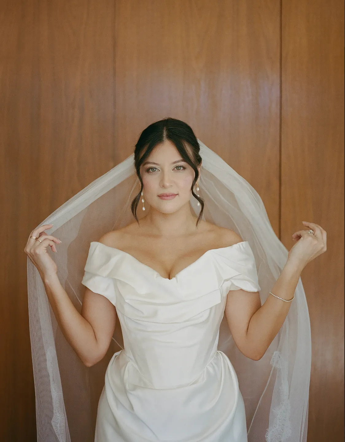 bride with natural hair and makeup look, wearing an off the shoulder bridal gown and cascading veil