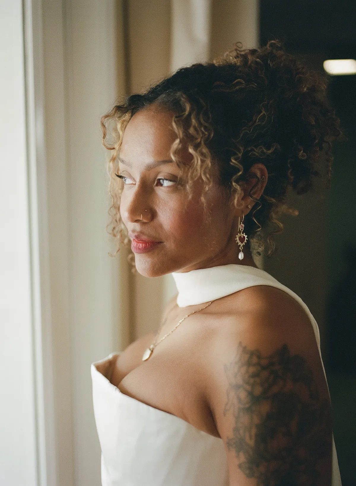 african american bride poses in bridal gown with scarf and soft glam makeup and naturally curly hair styled in an updo