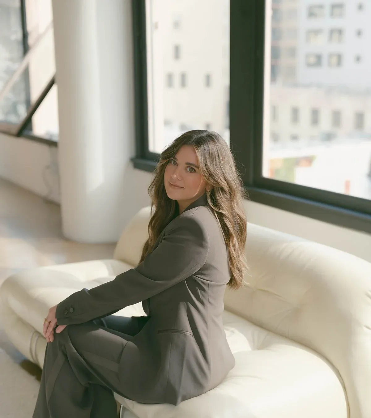 Founder Emily Wright seated on a cream sofa in a sunlit downtown loft