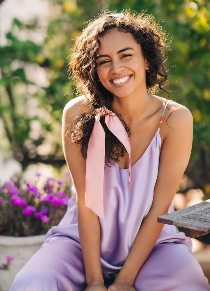 Model posing with natural makeup and her natural curls defined in naturally curly updo hairstyle.