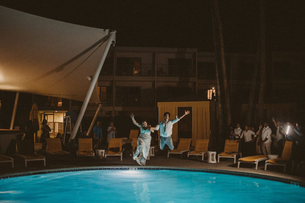 bride and groom jump into the hotel pool after reception