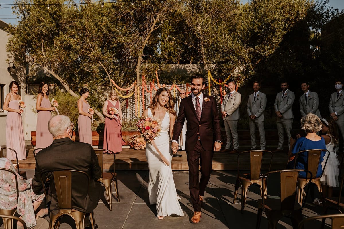 husband and wife walk down the isle together after wedding ceremony in southern california
