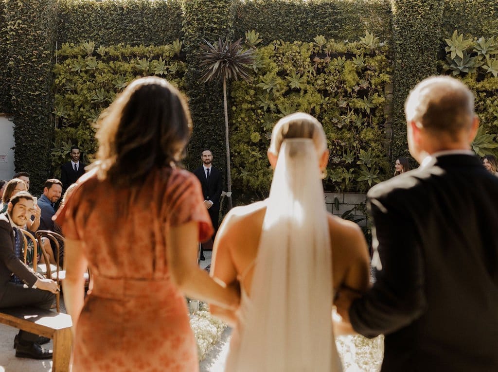 bride and her parents walk down the isle