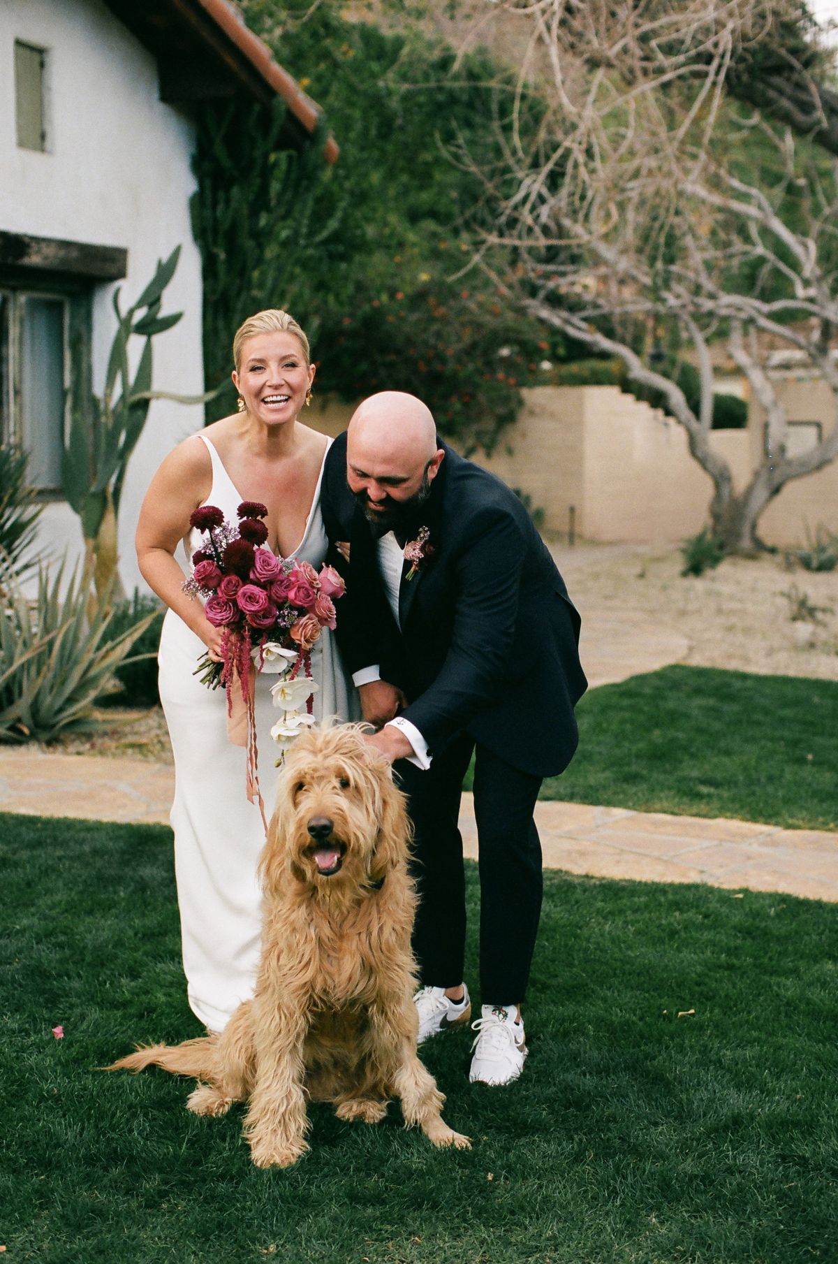 the happy couple pose with their adorable dog on their wedding day