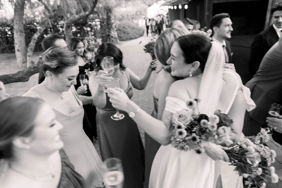 bride embraces with family and bridal party after getting married