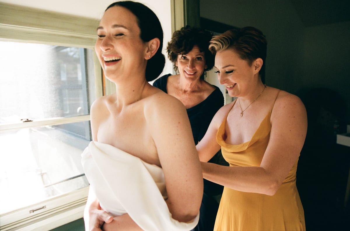 bride gets into her wedding dress with the help of her mom
