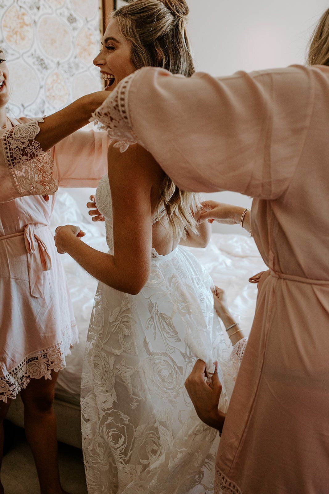 bride getting into wedding dress for her boho, malibu beach wedding