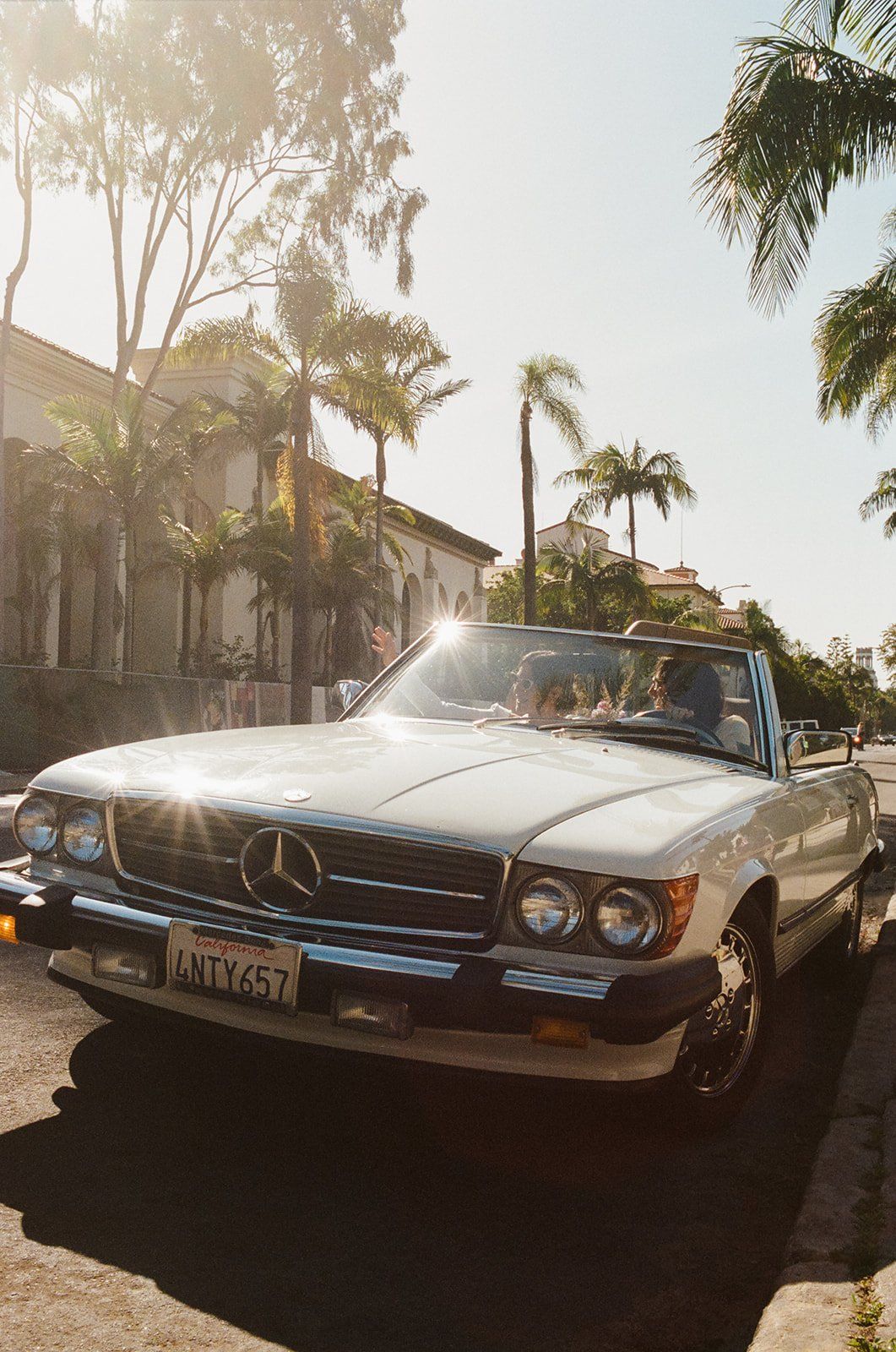same sex brides' drive off in their vintage convertible after their california wedding