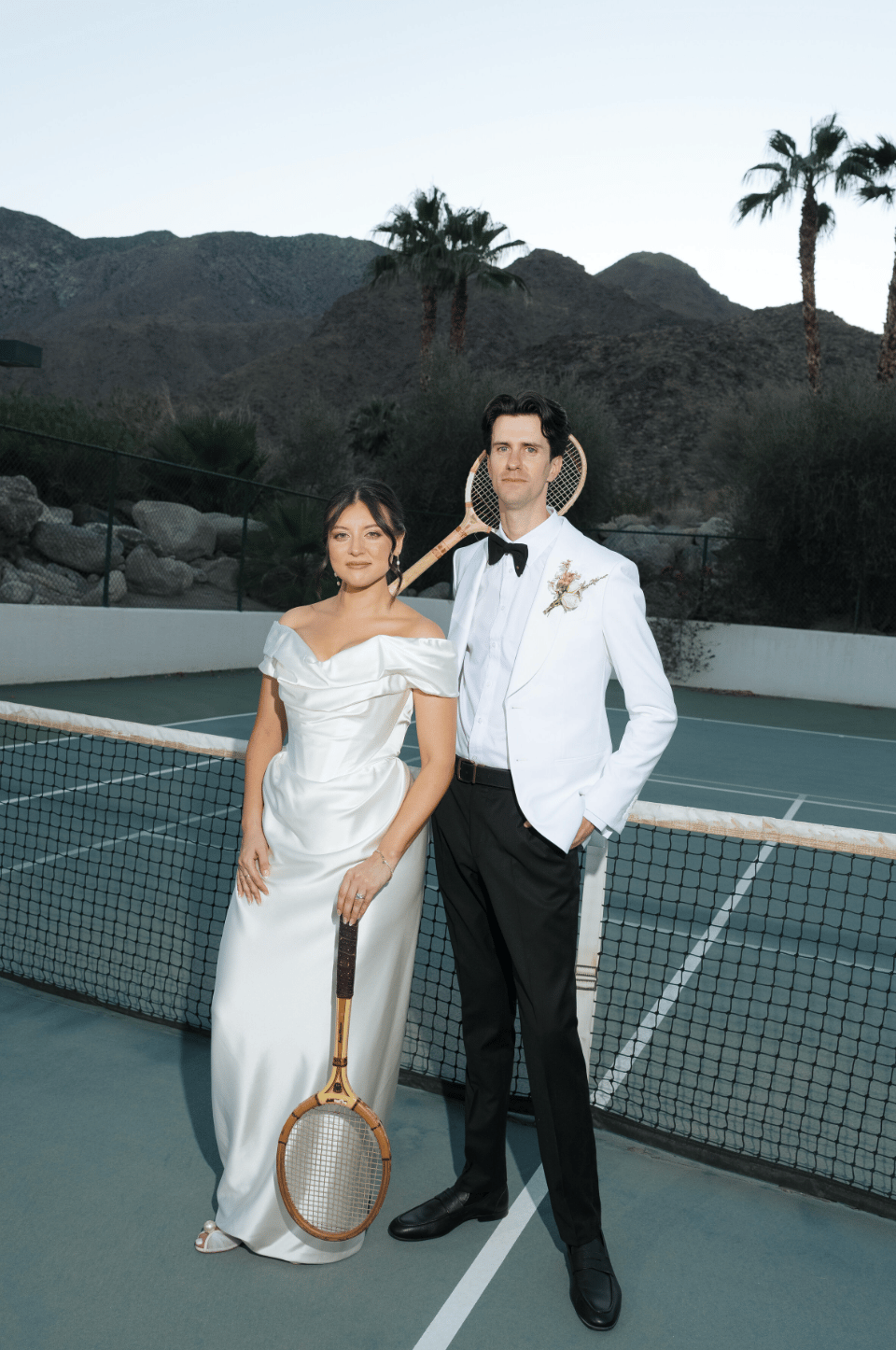 bride and groom posing for wedding day photos on the tennis court.